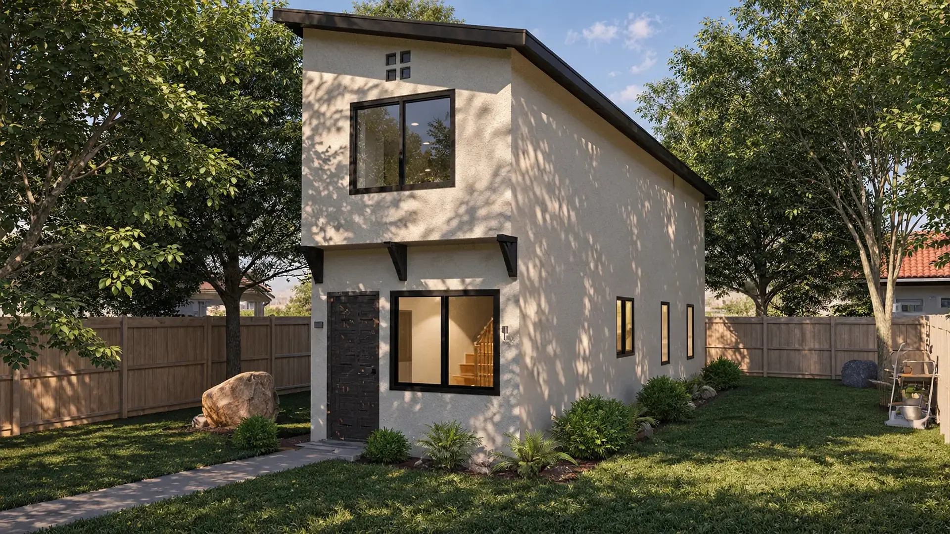 Rendering of the ADU 730 from its front corner in a fenced backyard: a narrow two-story unit in cream stucco under a dark single-slope roof, a dark front door at the corner with a wide black-framed window beside it, black brackets under the upper floor, a window centered above, and three narrow windows down the side wall.