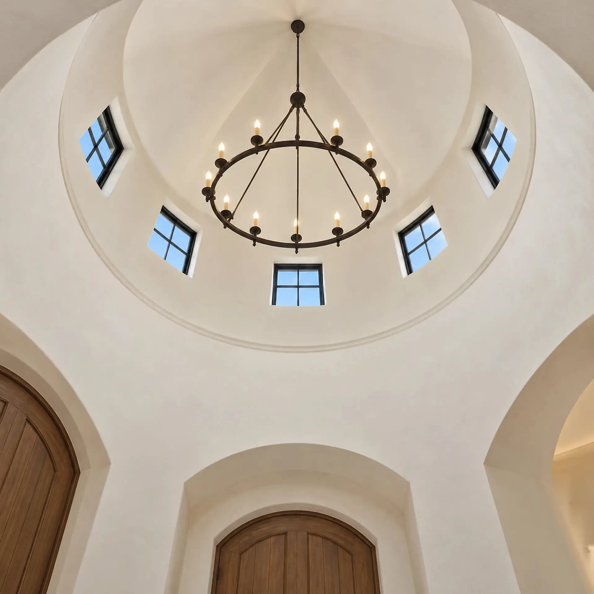 Rendering looking straight up inside the round entry tower: a domed plaster ceiling with an iron chandelier at the center and five small square windows around one side.